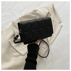 Detail of black quilted shoulder bag featuring 3D geometric patterns and adjustable strap