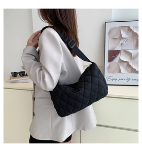 Detailed back view of a black quilted crossbody bag with adjustable strap on a model
