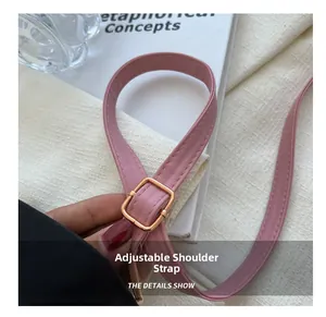 Detailed close-up of pink leather adjustable shoulder strap with gold metal buckle