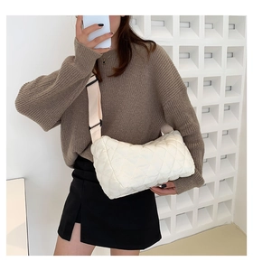 Detailed view of white quilted crossbody bag with stylish rhombus patterns and wide strap