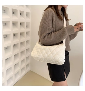 Close-up of white quilted puffer crossbody bag with classic diamond stitch texture