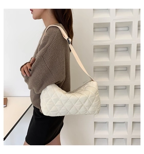 Detailed side view of white quilted shoulder bag with adjustable strap on model