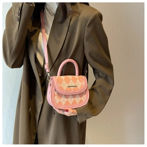 Detail of pink and beige quilted saddle bag with golden hardware and leather handle