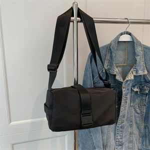 Black nylon crossbody pillow bag with adjustable wide strap shown with denim jacket