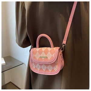 Detail of pink argyle quilted crossbody bag with gold hardware on a brown coat