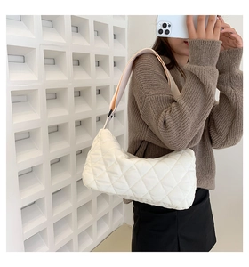 Detailed view of a white quilted crossbody bag with stylish rhombus patterns and wide strap