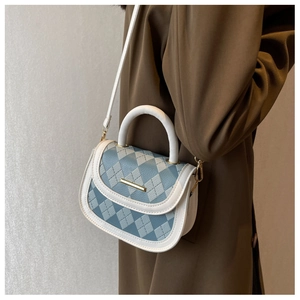 Detail of blue and white quilted leather saddle bag with gold metal trim and side view