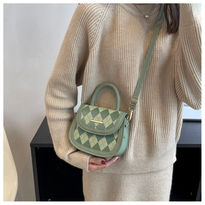 Detail of green quilted crossbody bag with gold metal trim and leather top handle