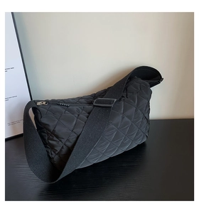 Macro shot of black quilted cloud crossbody bag with adjustable wide strap and zipper detail
