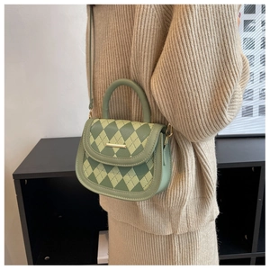 Close-up of a green quilted crossbody bag styled with a creamy knit dress for women