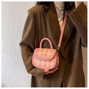 Detail of pink quilted handbag with gold accents and leather handle on a model