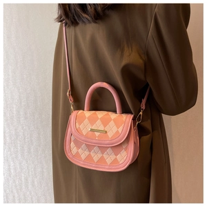 Quilted pink and beige crossbody saddle bag shown on model with gold metal detail