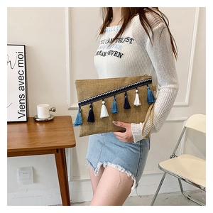 Detail of bohemian woven envelope clutch with blue tassels and wristlet strap