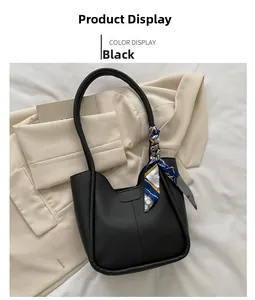 Détail de la poignée du cabas en similicuir noir ornée d'un élégant foulard en soie imprimé