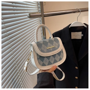 Detail of blue quilted pattern with gold buckle and white handle on elegant crossbody bag