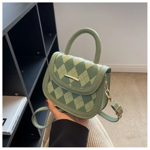 Close-up of light green argyle quilted handbag with golden bar metal closure