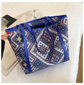 Detail of colorful geometric woven tote bag with durable blue leather handles and trim