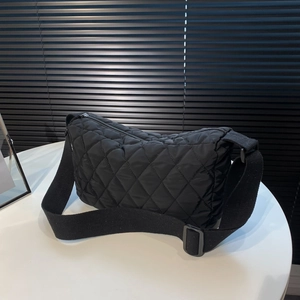 Modern black quilted rhombic crossbody bag with adjustable wide strap on white stand