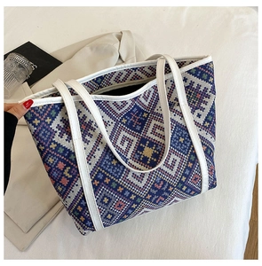 Close-up of geometric ethnic woven tote bag with white faux leather handles and edges
