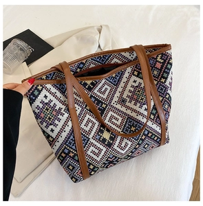 Close-up of geometric knit patterns and leather handles on ethnic tote bag