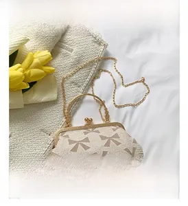 Close-up of retro beige crossbody bag with coffee bow patterns and gold chain