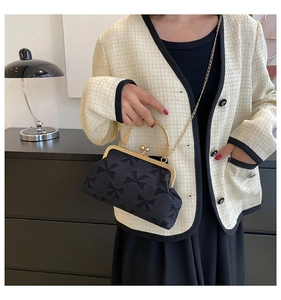 Detail of vintage black fabric crossbody bag with bow patterns and gold chain strap
