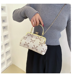 Detail of vintage cream handbag with bow pattern, gold handle and metal chain strap