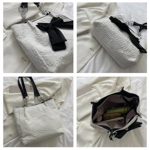 Détails d'un sac cabas plissé blanc avec nœud noir et bandoulière en chaîne argentée