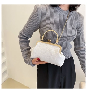 Close-up of white embossed floral handbag with gold metal handle and chain strap