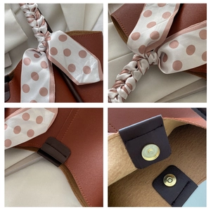 Detail of brown leather tote featuring woven handles and a polka dot silk scarf accent