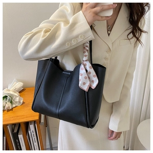 Detail of black large-capacity tote bag with pink polka dot scarf on a leather handle