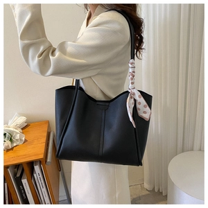Detail of black faux leather tote bag with brown polka dot silk scarf on woman shoulder