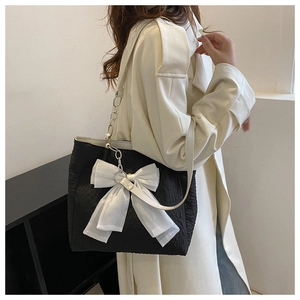 Détail du sac cabas plissé noir avec un grand nœud en organza blanc et une chaîne argentée