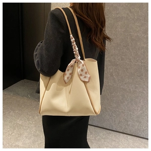 Detail of beige tote bag with brown trim and polka dot silk scarf on the handle