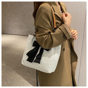 Détail du sac cabas plissé blanc avec grand nœud noir et bandoulière en chaîne argentée