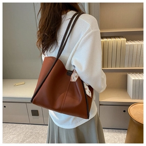 Detail of tan leather tote bag featuring a decorative polka dot scarf and slim straps
