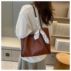 Brown vintage tote bag with polka dot scarf detail worn by model in cozy room