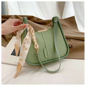 Détail du sac seau demi-lune vert avec foulard en soie floral et finitions dorées