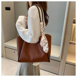 Detailed view of a brown faux leather tote bag with elegant polka dot silk scarf handle