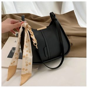 Détail du sac en cuir noir mat avec foulard décoratif en soie à motif cerises et chaîne dorée