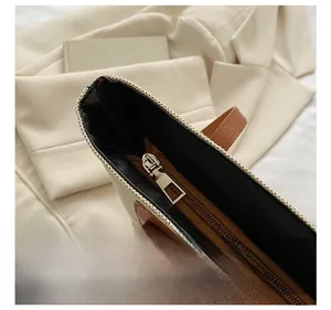 Detail of silver metal zipper closure and brown leather handles on a canvas tote bag