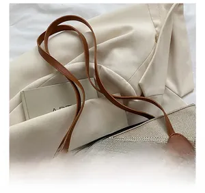 Detail of reinforced leather shoulder straps on a canvas tote bag with premium stitching