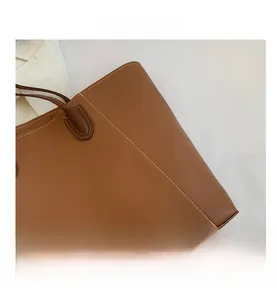 Detail of brown lychee-grain leather tote bag featuring elegant white contrast stitching