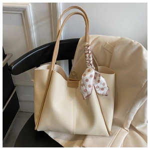 Close-up of cream white leather tote bag with light brown trim and decorative silk scarf