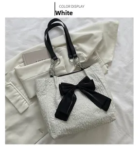 Détail du sac cabas blanc matelassé avec grand nœud noir et bandoulière en chaîne argentée
