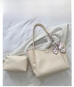 White leather tote bag set with pink polka dot scarf on a minimalist fabric background