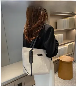 Minimalist beige canvas tote bag with black leather straps shown in a modern interior