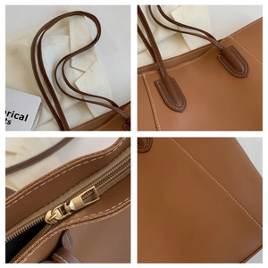 Detail view of brown tote bag with contrast stitching and golden zipper hardware