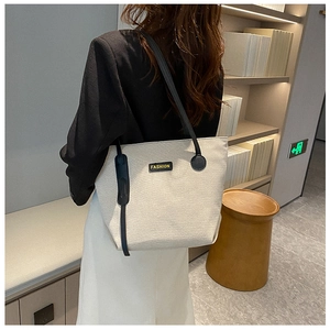 Cream canvas tote bag with black shoulder straps and Fashion leather patch detail