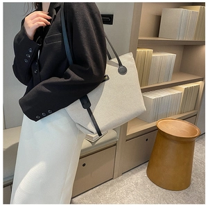 Minimalist canvas tote bag with black leather straps shown in a lifestyle office setting